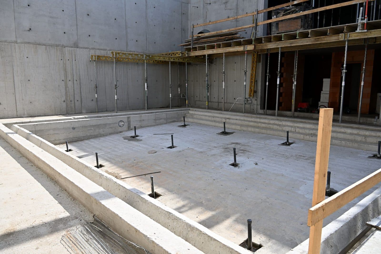 Betonová vana vnitřního bazénu na stavbě nového plaveckého stadionu v Písku, ještě bez obkladů, s lešením u stěny