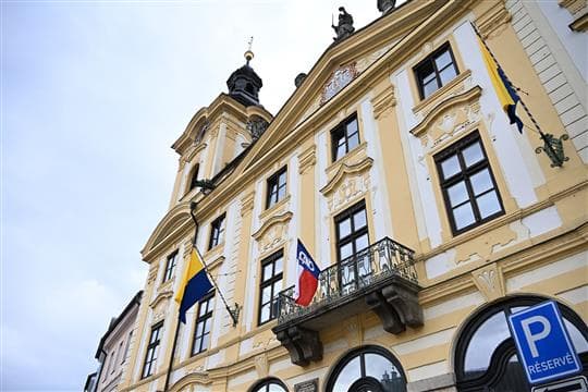 Žlutobílé průčelí písecké radnice s věžičkou, na balkonu visí vlajka Sokola s modrým klínem a sokolem, po stranách žlutomodré prapory